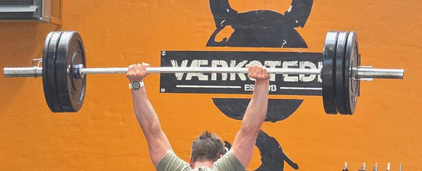 Mike Krohn locking out a barbell overhead at Værkstedet